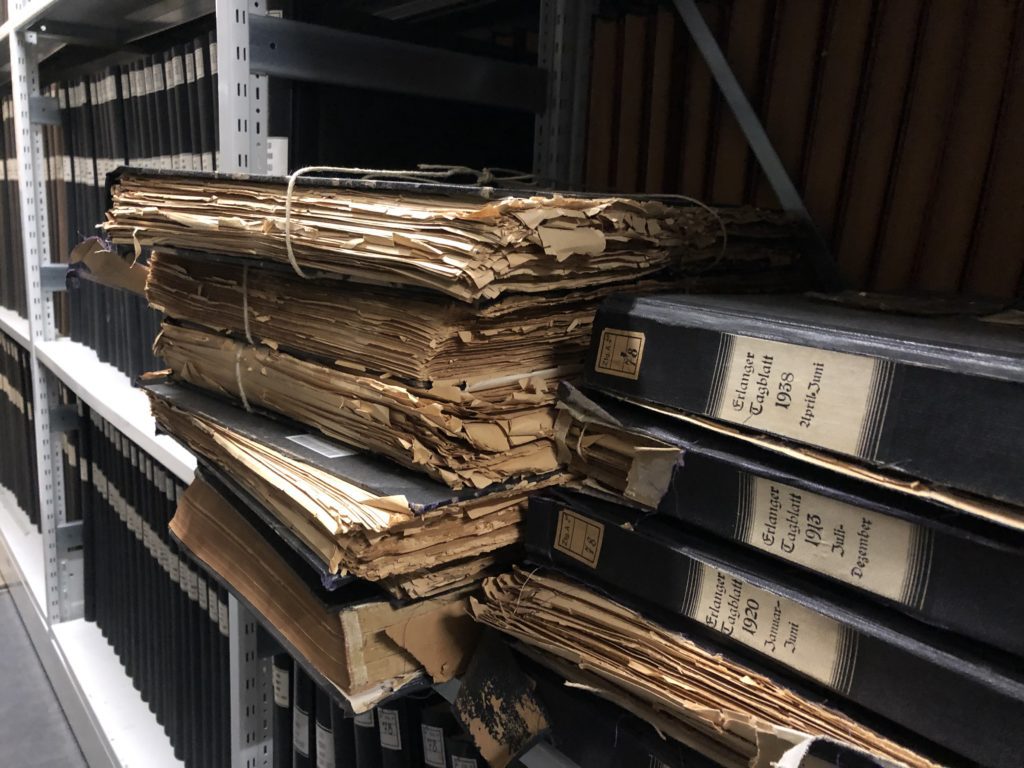 Abbildung einiger Zeitungsbände, die durch Säurefraß stark zerstört sind